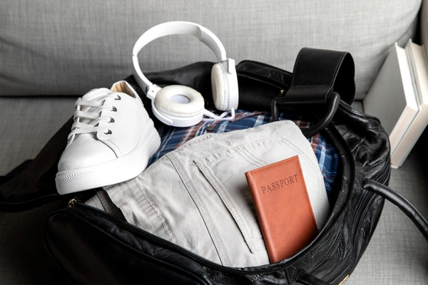Packed canvas travel bag with a fitness band, sunglasses and a passport on a hotel bench